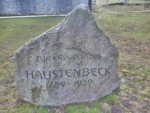 Der Stein befindet sich vor der ehemaligen Kirche des Dorfes Haustenbeck. Dieses wurde im Zuge der Vergrößerung des Militärübungsplatzes im Jahr 1939 aufgelöst. Die Bewohner des Ortes wurde damals umgesiedelt. Auch heute wird das Areal militärisch genutzt, es gehört zum Truppenübungsplatz-Senne. Auf dem Stein ist zu lesen : "Zur Erinnerung / Haustenbeck / 1659-1939"
